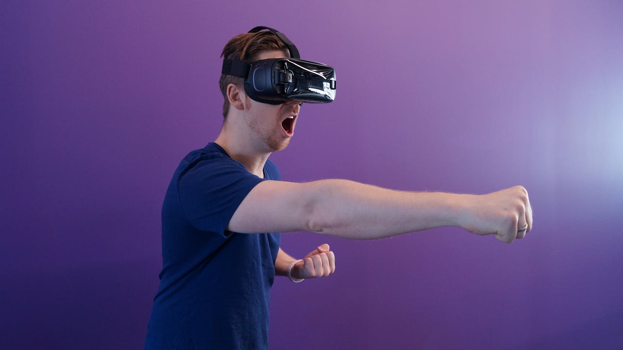 portfolio-02 Caucasian man immersed in virtual reality using VR headset, making a punching gesture against a purple backdrop.