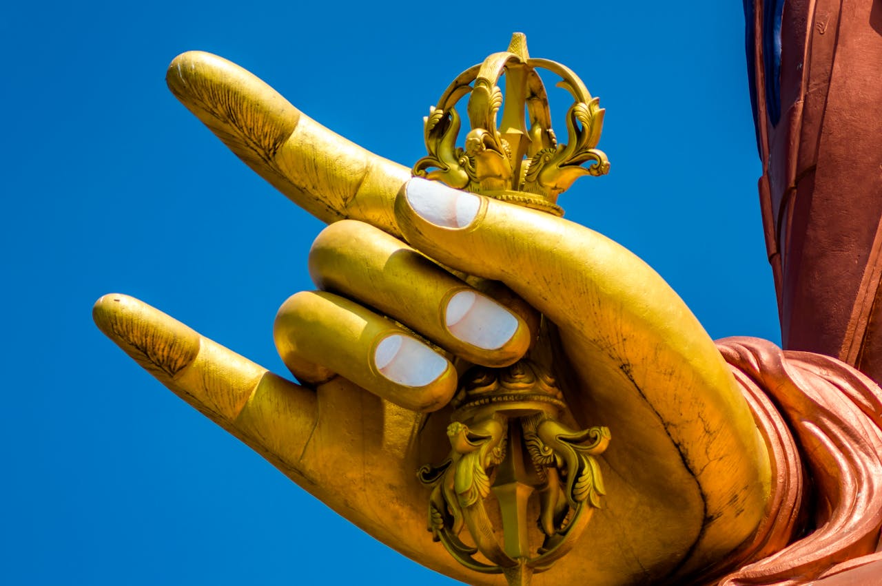Close-up of a golden Buddha hand statue holding a traditional symbol in South Sikkim, India.