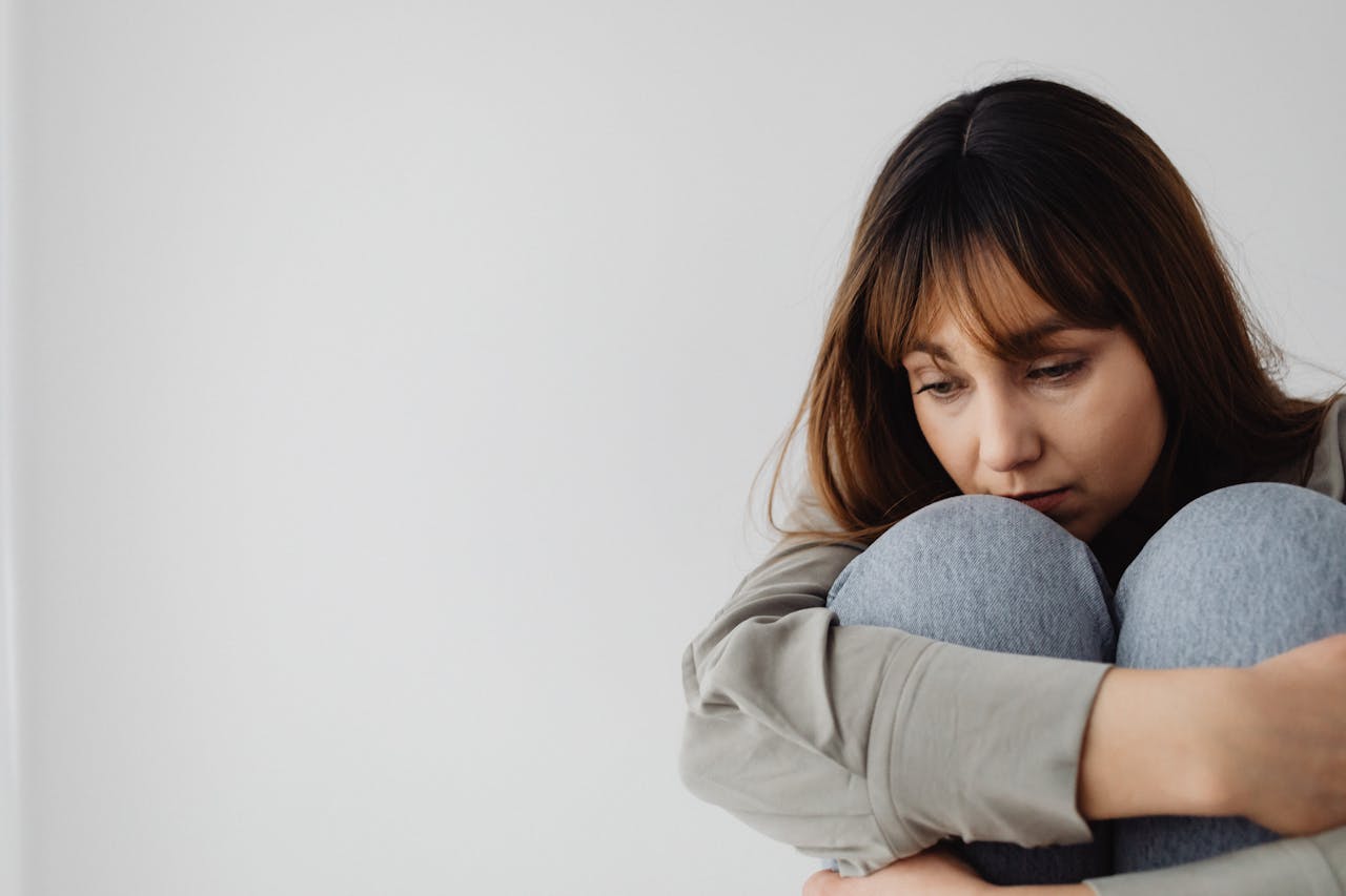 Caucasian woman sitting pensively indoors, capturing a moment of reflection and emotion.