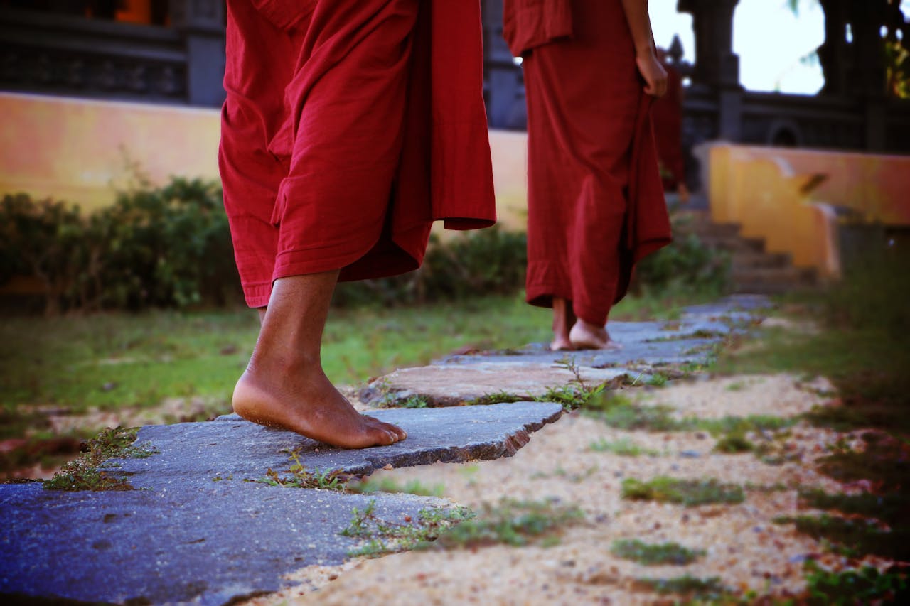 Buddhist monks walking barefoot on a stone path in Matara, Sri Lanka.