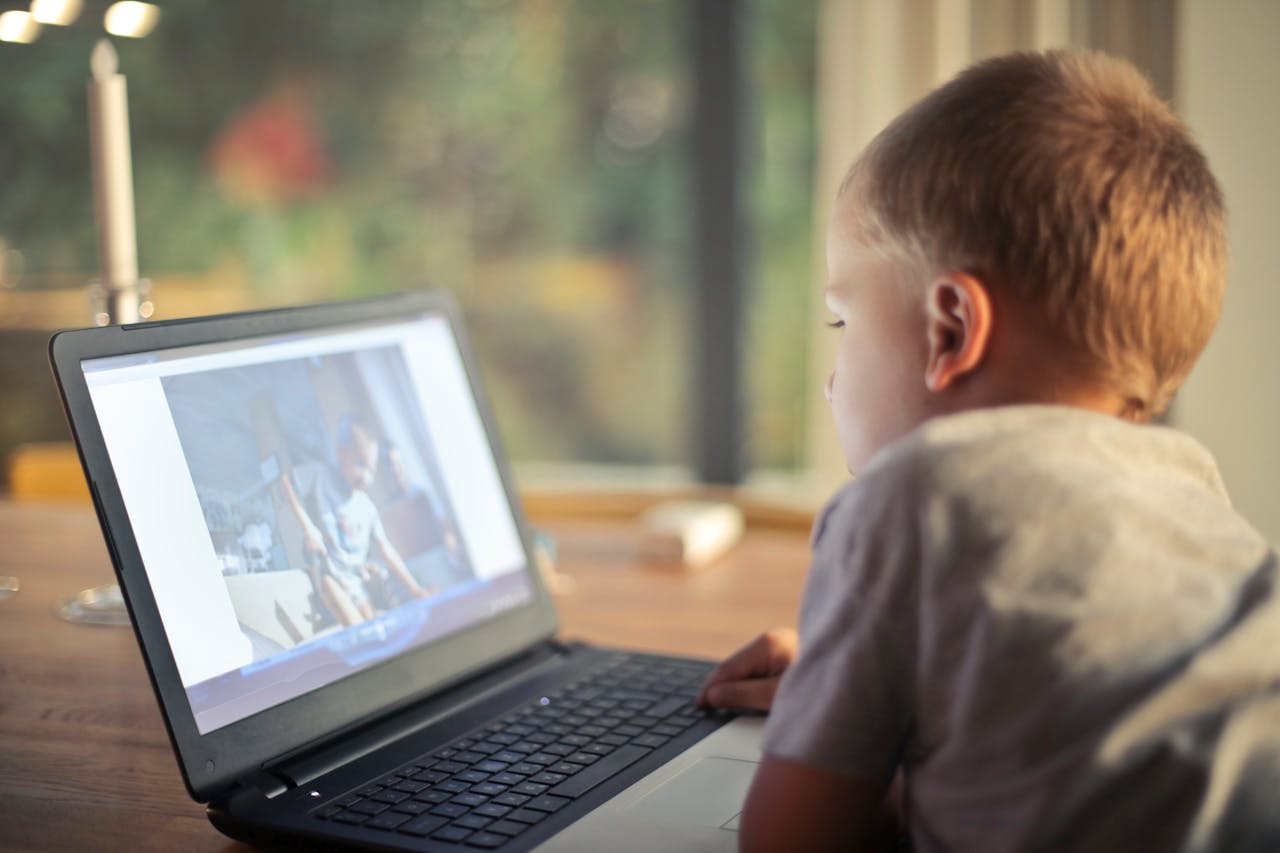 portfolio-07 A young boy engrossed in watching content on a laptop in a cozy home setting.